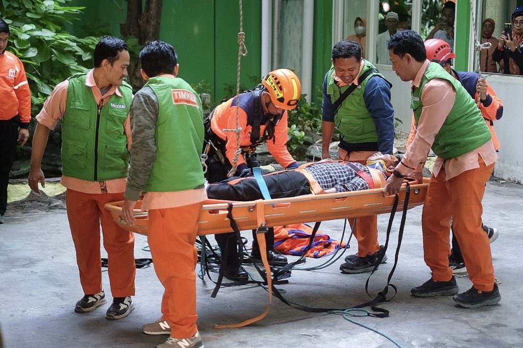 Karyawan sedang melakukan latihan evakuasi bersama lembaga simulasi bencana